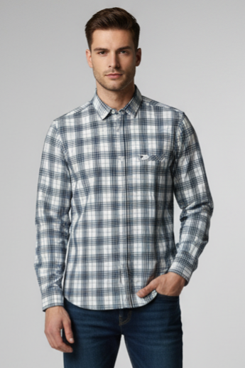 Man wearing a plaid shirt and jeans on a gray background